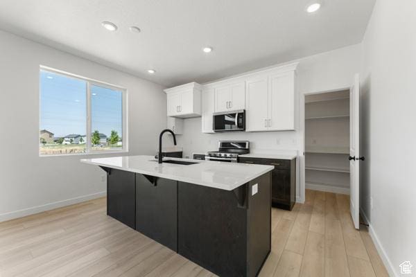 737 N Plainsman Dr Unit 108, Spanish Fork, UT 84660 - kitchen featuring stainless steel appliances, white cabinetry, light wood-style flooring, a center island with sink, and recessed lighting