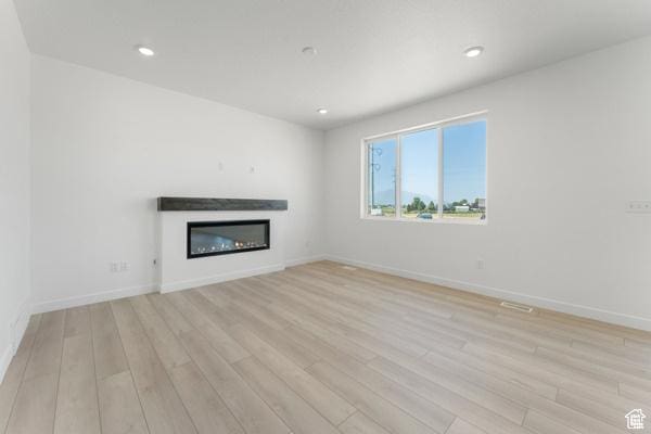737 N Plainsman Dr Unit 108, Spanish Fork, UT 84660 - unfurnished living room featuring light wood-style flooring, a glass covered fireplace, and recessed lighting