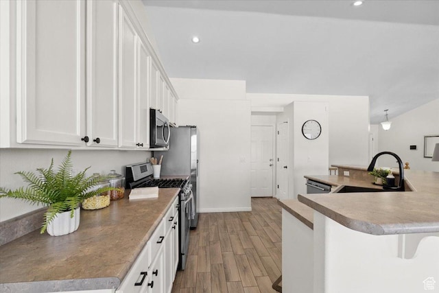 6515 S Mount Whitney Ln, West Valley City, UT 84118 - kitchen featuring appliances with stainless steel finishes, light wood-style floors, white cabinets, a kitchen breakfast bar, and recessed lighting