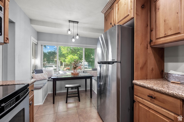 717 E 150 S, Provo, UT 84606 - kitchen featuring stainless steel appliances, light stone counters, light tile patterned floors, brown cabinets, and decorative light fixtures
