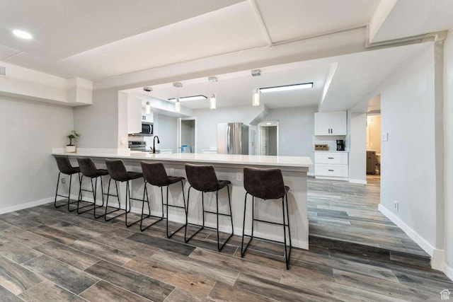 211 N 800 E, Bountiful, UT 84010 - kitchen with stainless steel appliances, white cabinetry, a breakfast bar area, a peninsula, and dark wood-type flooring