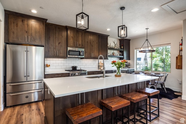3302 Quarry Springs Dr, Park City, UT 84098 - kitchen with stainless steel appliances, dark brown cabinetry, wood finished floors, decorative backsplash, and recessed lighting