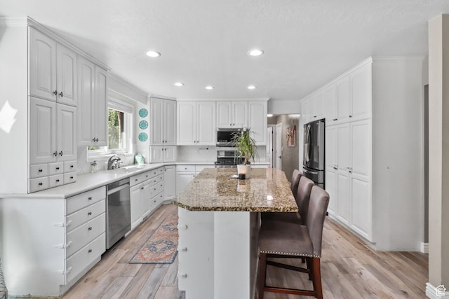 9618 S Ruskin Cir E, Sandy, UT 84092 - kitchen featuring stainless steel appliances, a center island, light wood-type flooring, white cabinets, and a kitchen bar
