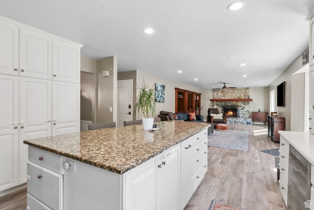 9618 S Ruskin Cir E, Sandy, UT 84092 - kitchen featuring a stone fireplace, light wood-type flooring, a kitchen island, recessed lighting, and white cabinets