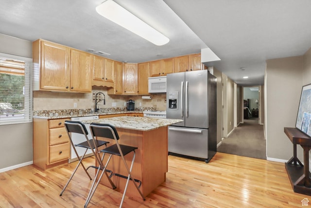 9618 S Ruskin Cir E, Sandy, UT 84092 - kitchen with white appliances, a center island, light wood-type flooring, light brown cabinets, and backsplash