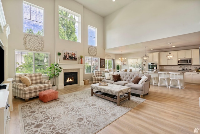 598 W Sandhill Dr, Lehi, UT 84043 - living room featuring a glass covered fireplace, light wood-type flooring, a high ceiling, recessed lighting, and a chandelier