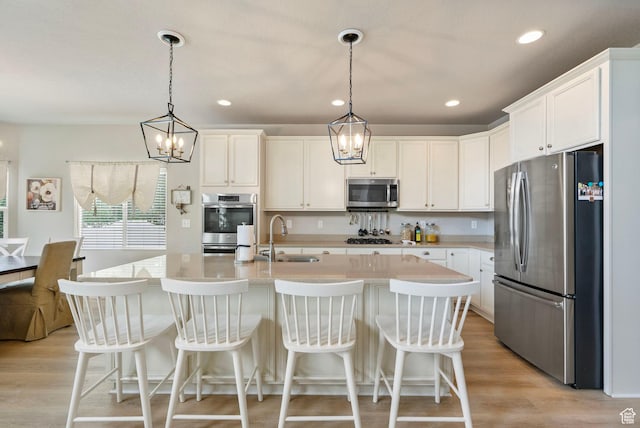 598 W Sandhill Dr, Lehi, UT 84043 - kitchen featuring stainless steel appliances, light countertops, light wood-style flooring, white cabinets, and hanging light fixtures