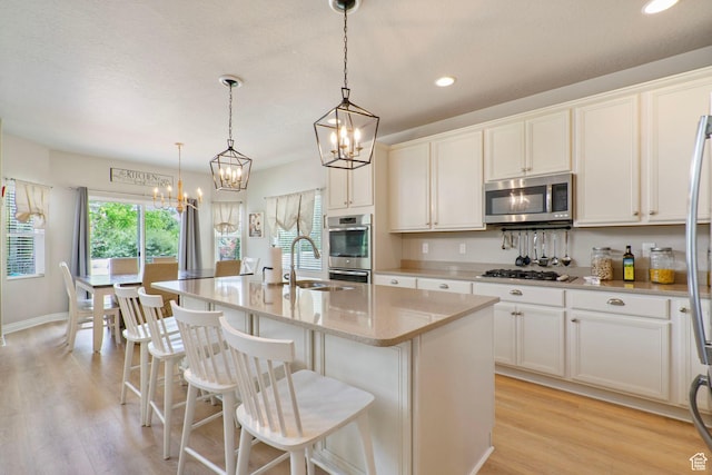 598 W Sandhill Dr, Lehi, UT 84043 - kitchen with appliances with stainless steel finishes, a chandelier, a kitchen island with sink, recessed lighting, and light wood-style flooring
