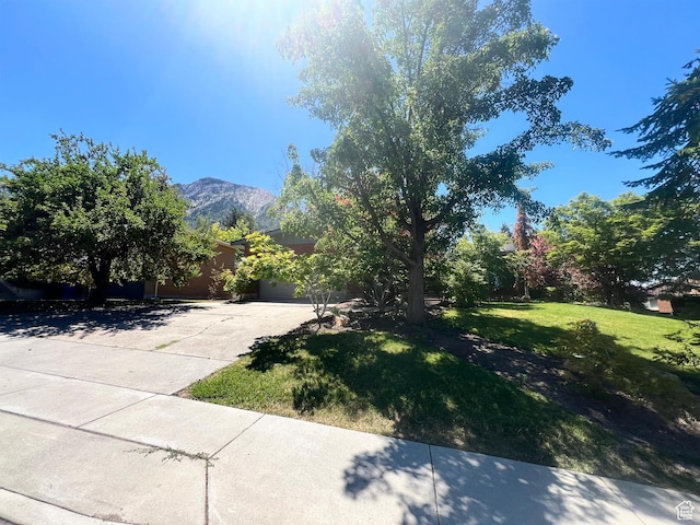3550 E Oakview Dr, Millcreek, UT 84124 - view of green lawn with driveway, a mountain view, and a garage