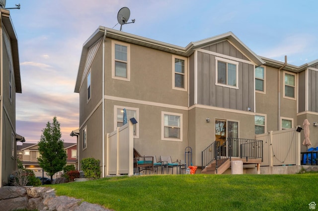14584 S Heatherly Ln, Herriman, UT 84096 - back of property at dusk with board and batten siding, a yard, and stucco siding