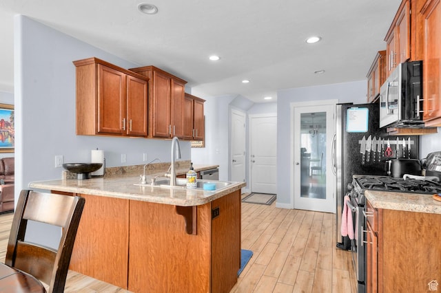 14584 S Heatherly Ln, Herriman, UT 84096 - kitchen with stainless steel appliances, brown cabinetry, a peninsula, light wood finished floors, and recessed lighting