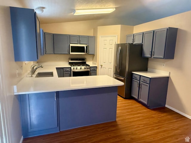 428 E 810 N, Tooele, UT 84074 - kitchen featuring appliances with stainless steel finishes, a peninsula, wood finished floors, vaulted ceiling, and light countertops