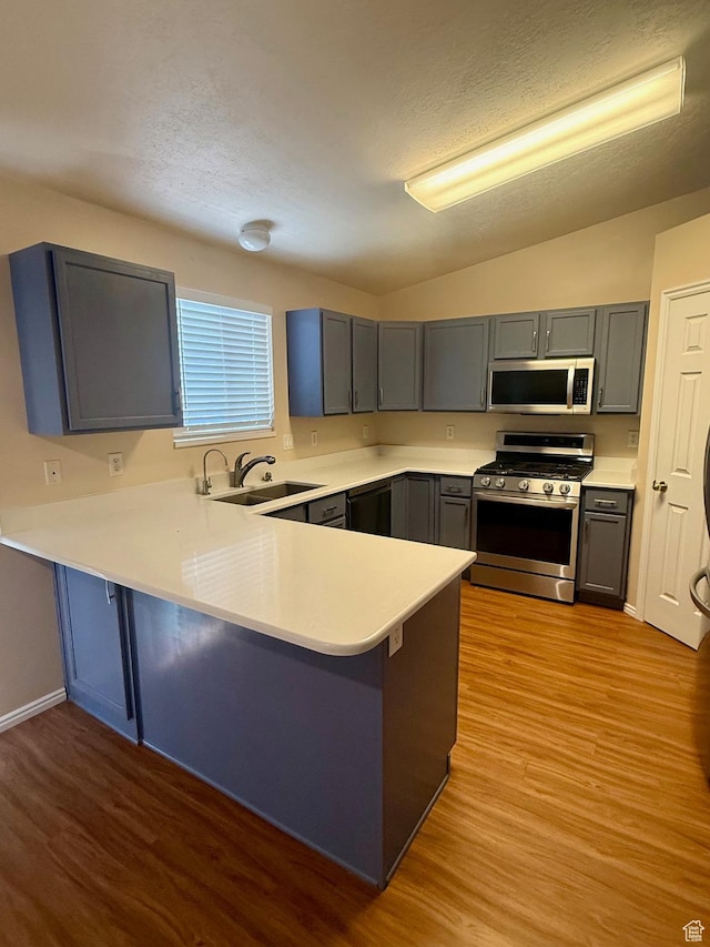 428 E 810 N, Tooele, UT 84074 - kitchen with appliances with stainless steel finishes, wood finished floors, a peninsula, light countertops, and gray cabinetry