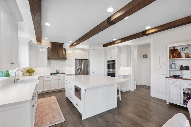 10865 S Hiddenwood Dr, Sandy, UT 84092 - kitchen with custom range hood, stainless steel appliances, beamed ceiling, white cabinets, and decorative backsplash
