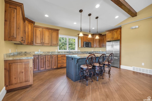 10865 S Hiddenwood Dr, Sandy, UT 84092 - kitchen with stainless steel appliances, brown cabinets, a breakfast bar area, beamed ceiling, and a center island