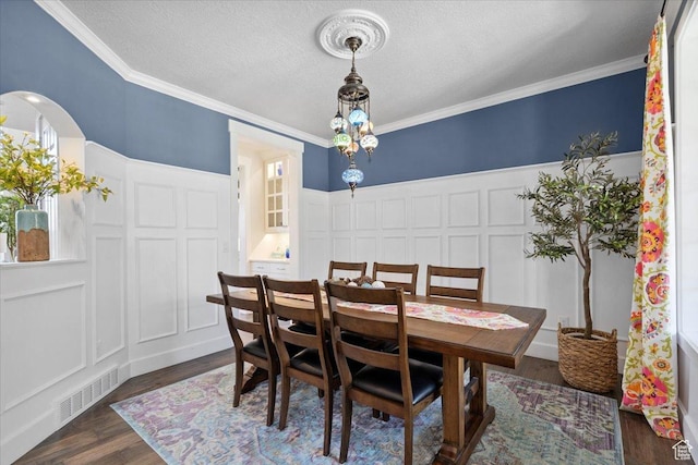 10865 S Hiddenwood Dr, Sandy, UT 84092 - dining space with a decorative wall, dark wood-type flooring, ornamental molding, a textured ceiling, and arched walkways