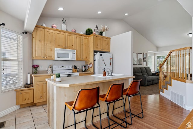 623 W 550 S, Centerville, UT 84014 - kitchen with white appliances, vaulted ceiling, light brown cabinetry, light countertops, and a kitchen breakfast bar