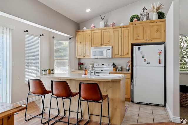623 W 550 S, Centerville, UT 84014 - kitchen featuring white appliances, light countertops, a kitchen island with sink, a breakfast bar area, and light brown cabinetry