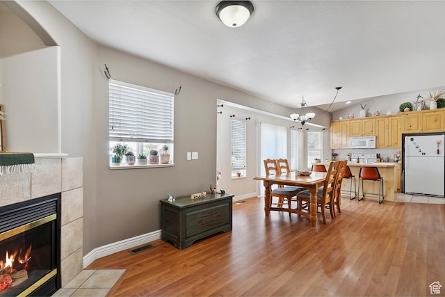 623 W 550 S, Centerville, UT 84014 - dining room with light wood-style flooring, a chandelier, lofted ceiling, a tiled fireplace, and arched walkways