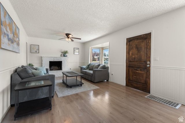 2536 S 1000 W, Syracuse, UT 84075 - living area with a textured ceiling, ceiling fan, wainscoting, wood finished floors, and a premium fireplace