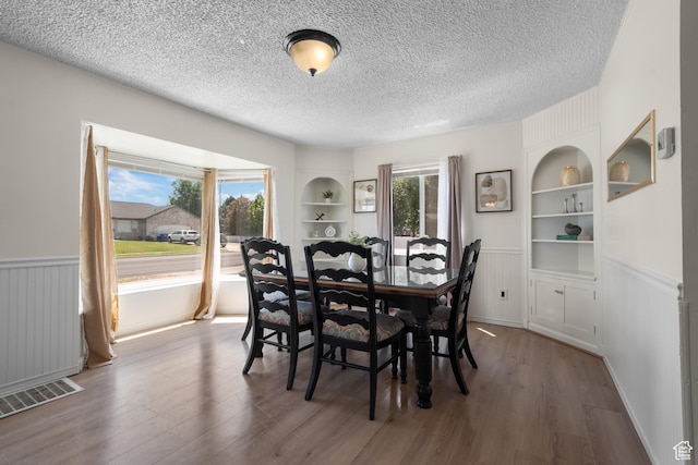2536 S 1000 W, Syracuse, UT 84075 - dining room featuring built in shelves, a textured ceiling, wood finished floors, and wainscoting
