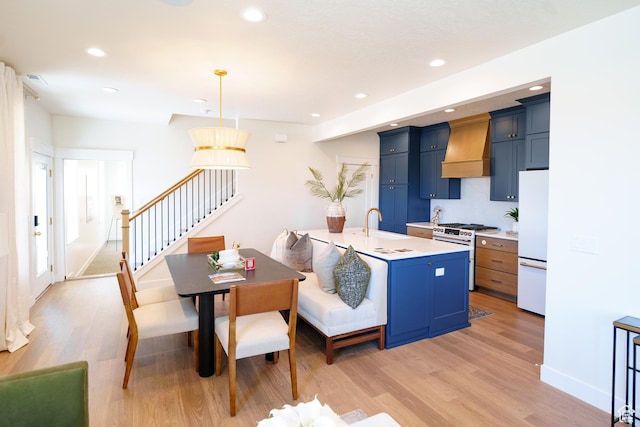11448 S Watercourse Rd, South Jordan, UT 84009 - kitchen with high end stainless steel range, custom exhaust hood, freestanding refrigerator, blue cabinetry, and light countertops