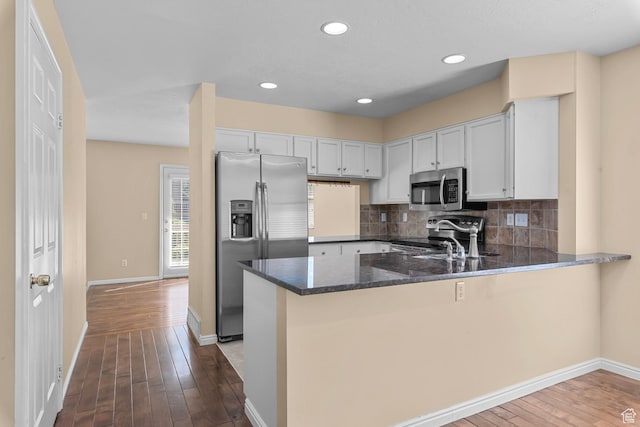 3548 E Wasatch Hills Ln S, Cottonwood Heights, UT 84121 - kitchen featuring stainless steel appliances, dark stone counters, a peninsula, dark wood finished floors, and decorative backsplash