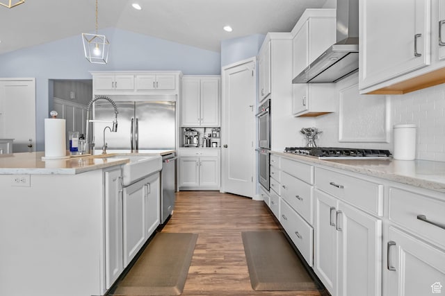 7603 S Scenic Maple Dr S, West Jordan, UT 84081 - kitchen featuring wall chimney range hood, stainless steel appliances, backsplash, white cabinetry, and lofted ceiling