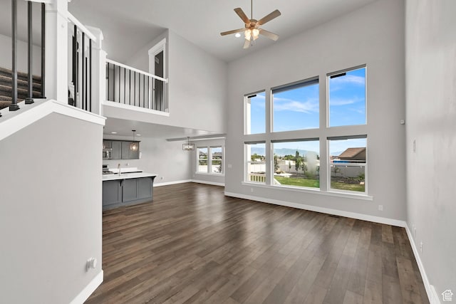 9602 N Blue Sky Dr, Eagle Mountain, UT 84005 - unfurnished living room with a ceiling fan, a high ceiling, dark wood-style flooring, and stairway