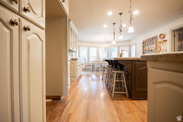 13251 S 1162 E, Draper, UT 84020 - kitchen with ornamental molding, a kitchen breakfast bar, a chandelier, glass insert cabinets, and light wood-type flooring
