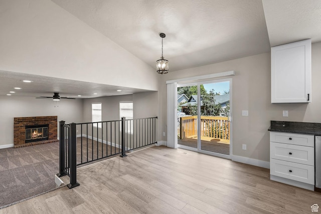 155 N 1600 W, West Point, UT 84015 - unfurnished dining area with light wood finished floors, a ceiling fan, a textured ceiling, vaulted ceiling, and a brick fireplace