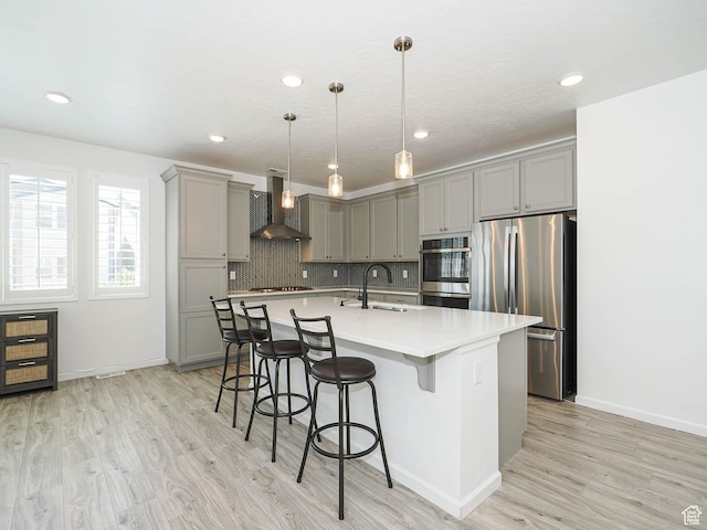 609 E 460 S, American Fork, UT 84003 - kitchen with gray cabinetry, wall chimney range hood, stainless steel appliances, light wood-type flooring, and a kitchen breakfast bar