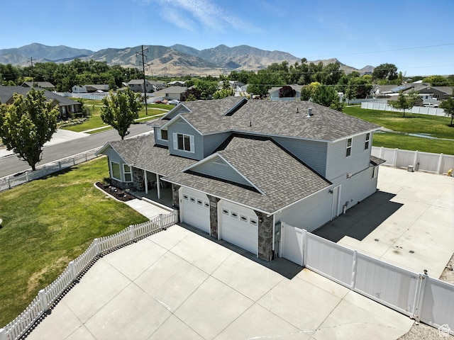 3036 S Dovetail Dr, West Valley City, UT 84128 - view of front facade featuring stone siding, a mountain view, a fenced backyard, and a garage