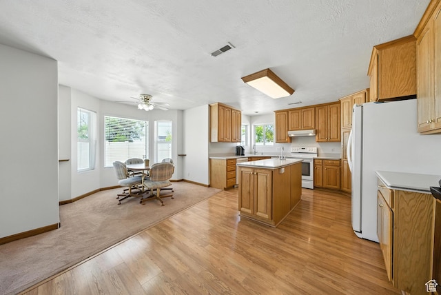 3036 S Dovetail Dr, West Valley City, UT 84128 - kitchen with white electric stove, light wood-type flooring, a center island with sink, ceiling fan, and light countertops