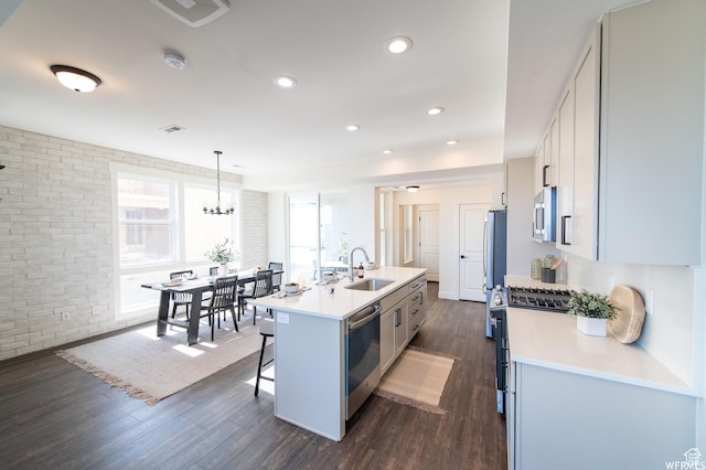 11556 S Watercourse Rd, South Jordan, UT 84009 - kitchen featuring appliances with stainless steel finishes, a breakfast bar area, dark wood-style flooring, light countertops, and a center island with sink