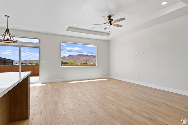 169 N 3670 W, Hurricane, UT 84737 - unfurnished living room with a raised ceiling, light wood-type flooring, a chandelier, a ceiling fan, and recessed lighting