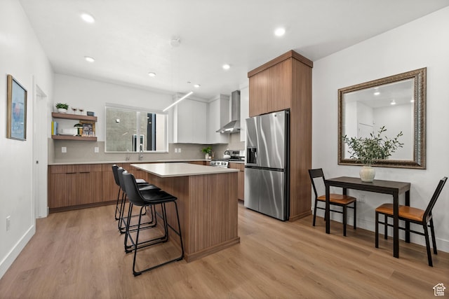 765 N 400 W Unit 205, Salt Lake City, UT 84103 - kitchen with stainless steel fridge, wall chimney range hood, a center island, light wood finished floors, and a kitchen bar