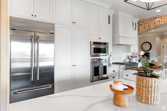 1557 S Stone Cliff Dr, St George, UT 84790 - kitchen with stainless steel appliances, white cabinetry, decorative backsplash, glass insert cabinets, and light stone counters