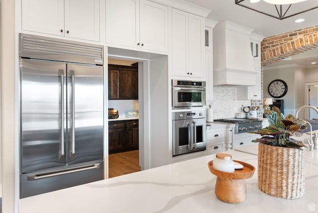 1557 S Stone Cliff Dr, St George, UT 84790 - kitchen with stainless steel appliances, white cabinetry, light stone countertops, glass insert cabinets, and decorative backsplash