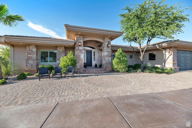 1557 S Stone Cliff Dr, St George, UT 84790 - view of front of house with stone siding, an attached garage, stucco siding, and driveway