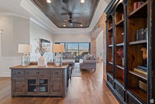 1557 S Stone Cliff Dr, St George, UT 84790 - living area featuring a raised ceiling, arched walkways, wood-type flooring, ceiling fan, and a wainscoted wall
