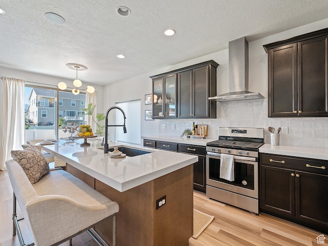 2148 E 970 N, Spanish Fork, UT 84660 - kitchen with stainless steel range with gas stovetop, wall chimney exhaust hood, light wood-type flooring, light countertops, and a textured ceiling