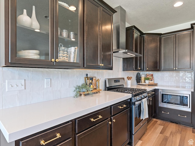 2148 E 970 N, Spanish Fork, UT 84660 - kitchen with appliances with stainless steel finishes, wall chimney range hood, dark brown cabinets, light wood-style flooring, and a textured ceiling