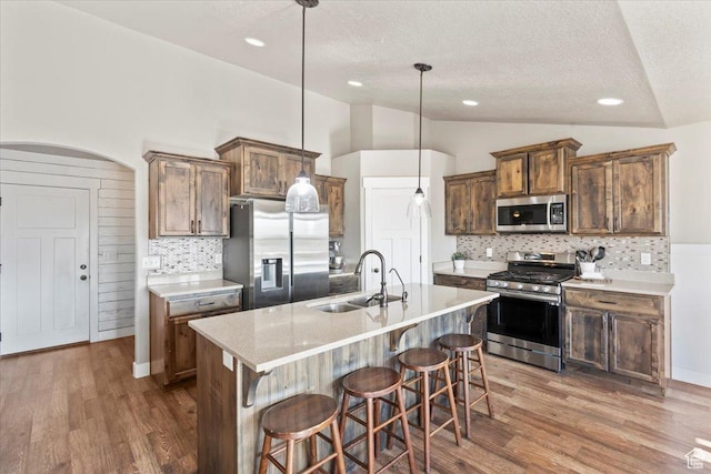 1608 S Terrace Rd, Saratoga Springs, UT 84045 - kitchen with appliances with stainless steel finishes, lofted ceiling, a textured ceiling, decorative backsplash, and a breakfast bar area