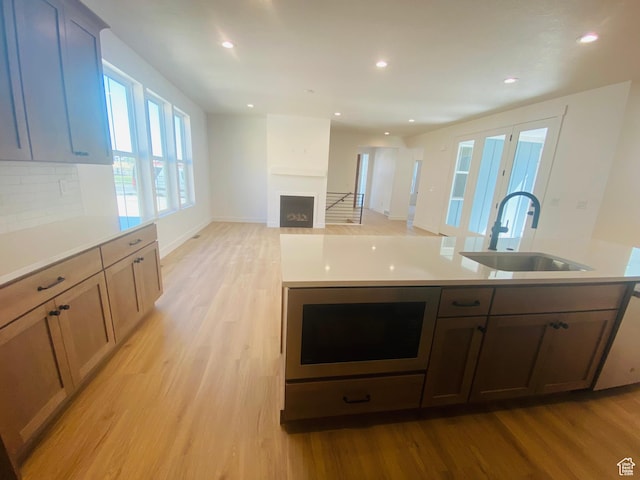 6511 W Lake Ave, South Jordan, UT 84009 - kitchen with a fireplace, light wood-style flooring, decorative backsplash, light countertops, and recessed lighting