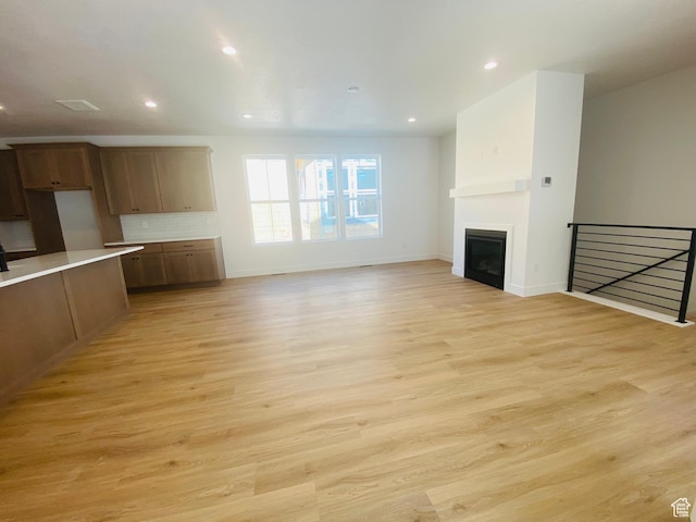 6511 W Lake Ave, South Jordan, UT 84009 - unfurnished living room with light wood-type flooring, a glass covered fireplace, and recessed lighting