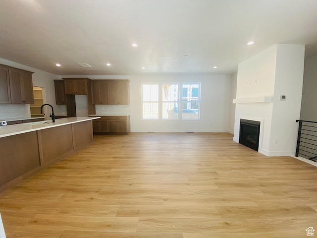 6511 W Lake Ave, South Jordan, UT 84009 - kitchen featuring a glass covered fireplace, backsplash, light countertops, recessed lighting, and light wood finished floors