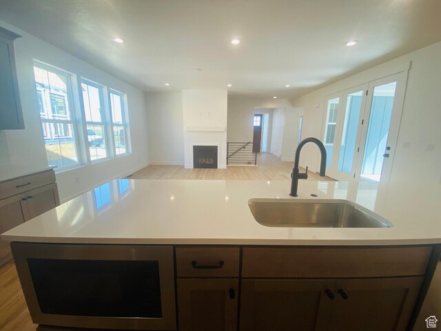 6511 W Lake Ave, South Jordan, UT 84009 - kitchen with a fireplace, stainless steel microwave, light wood-style floors, light countertops, and recessed lighting