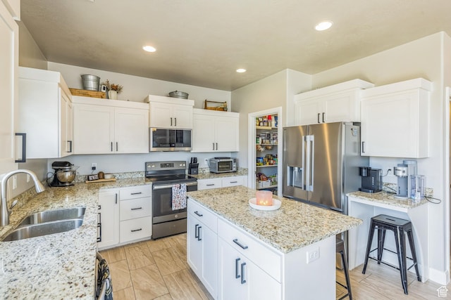150 N 1100 E Unit 63, Washington, UT 84780 - kitchen featuring stainless steel appliances, a kitchen island, white cabinetry, a kitchen bar, and light stone counters