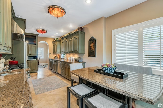 1120 E Yale Ave, Salt Lake City, UT 84105 - kitchen featuring stainless steel appliances, arched walkways, range hood, green cabinetry, and stone countertops
